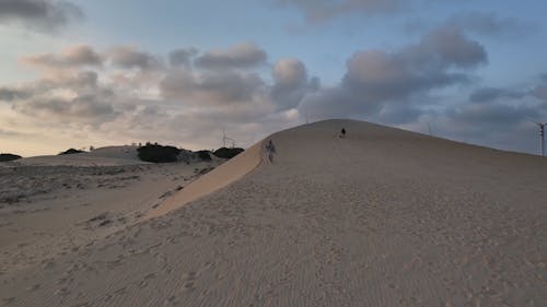 Drone Footage of Two People Walking on a Sand Dune 