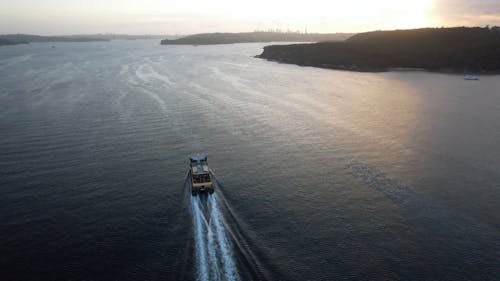 Drone Footage of a Ferry Sailing near the Coast at Sunset 