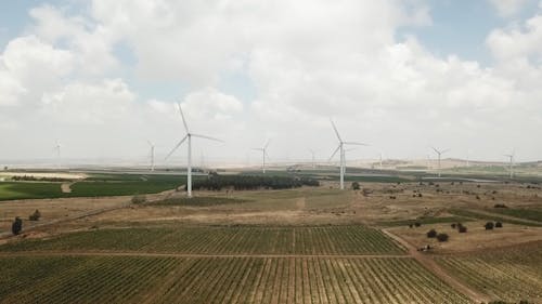 Drone Footage of Wind Turbines and Farm Fields under a Cloudy Sky