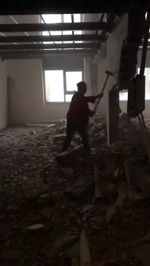 Man Demolishing a Wall of a Building