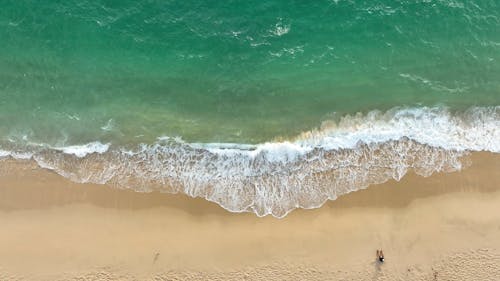 Top View of Breaking Waves on a Sandy Beach