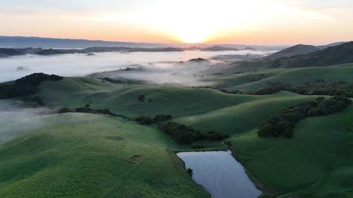 Drone Footage of Foggy Green Hills at Sunrise