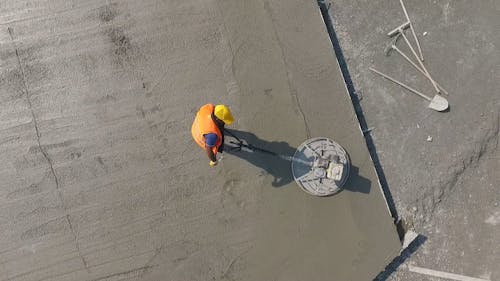 A Construction Worker Using a Concrete Leveling Machine