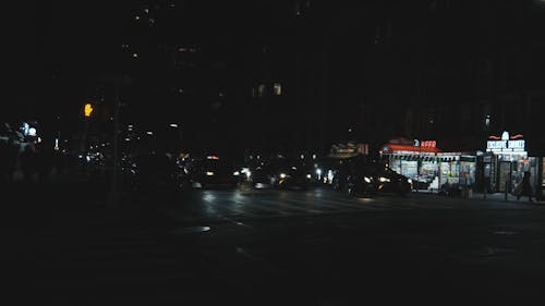 Night time cars with headlights drive through an intersection