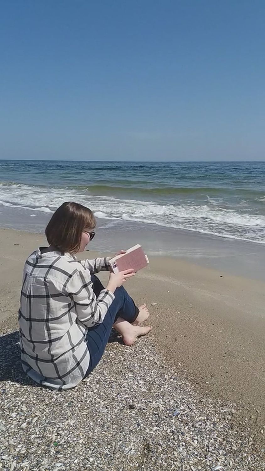 A woman sitting on the beach reading a book Free Stock Video Footage ...
