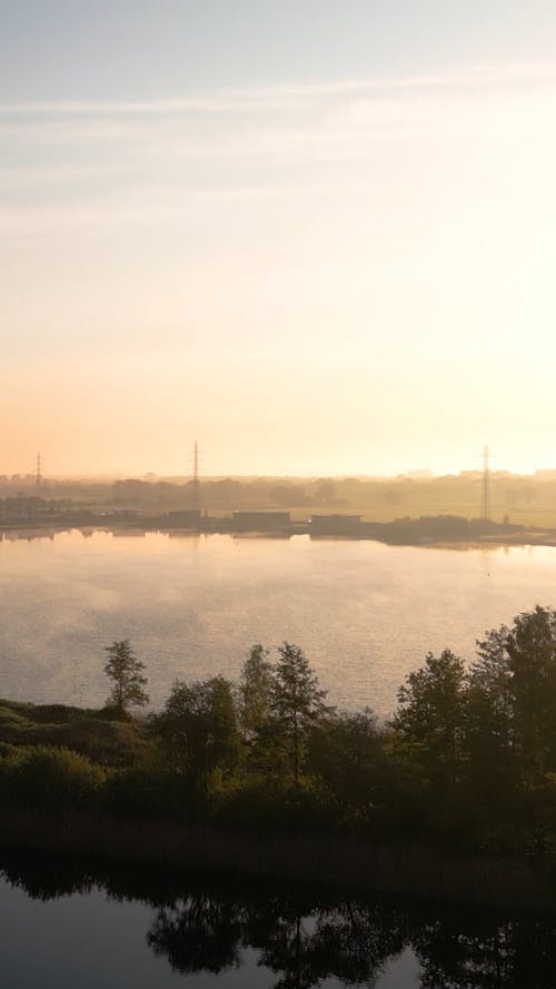 Drone Footage of a Lake in a Rural Area at Sunrise 