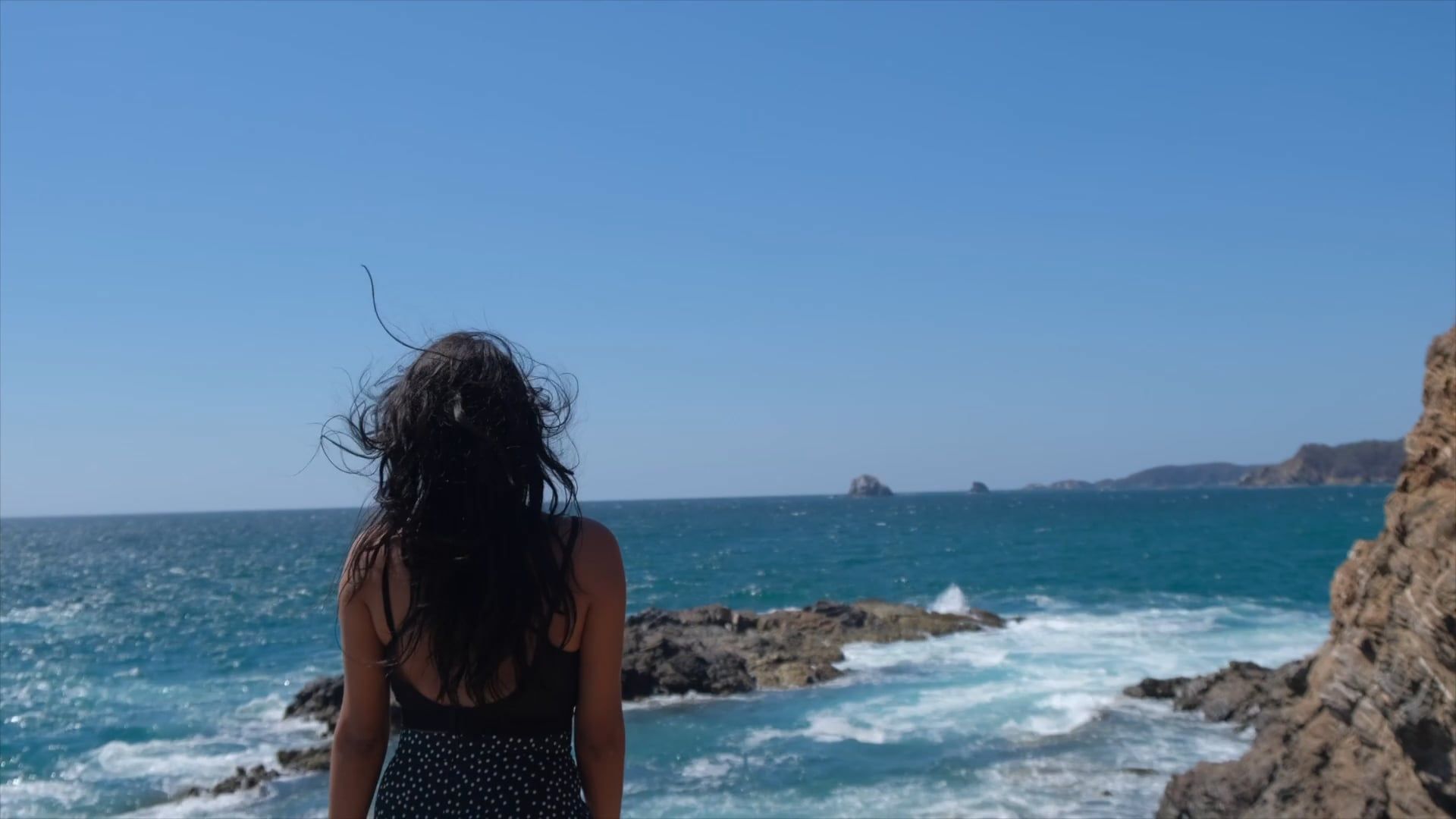 A woman standing on the rocks looking out to the ocean Free Stock Video ...