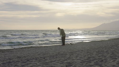 Young man using metal detector a the beach