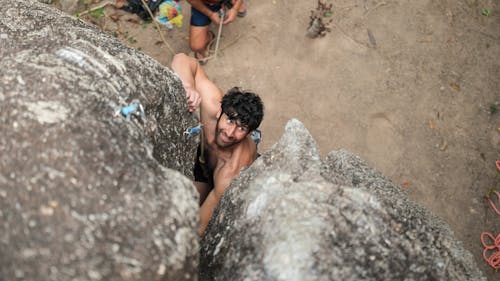 A Shirtless Man Climbing a Rock