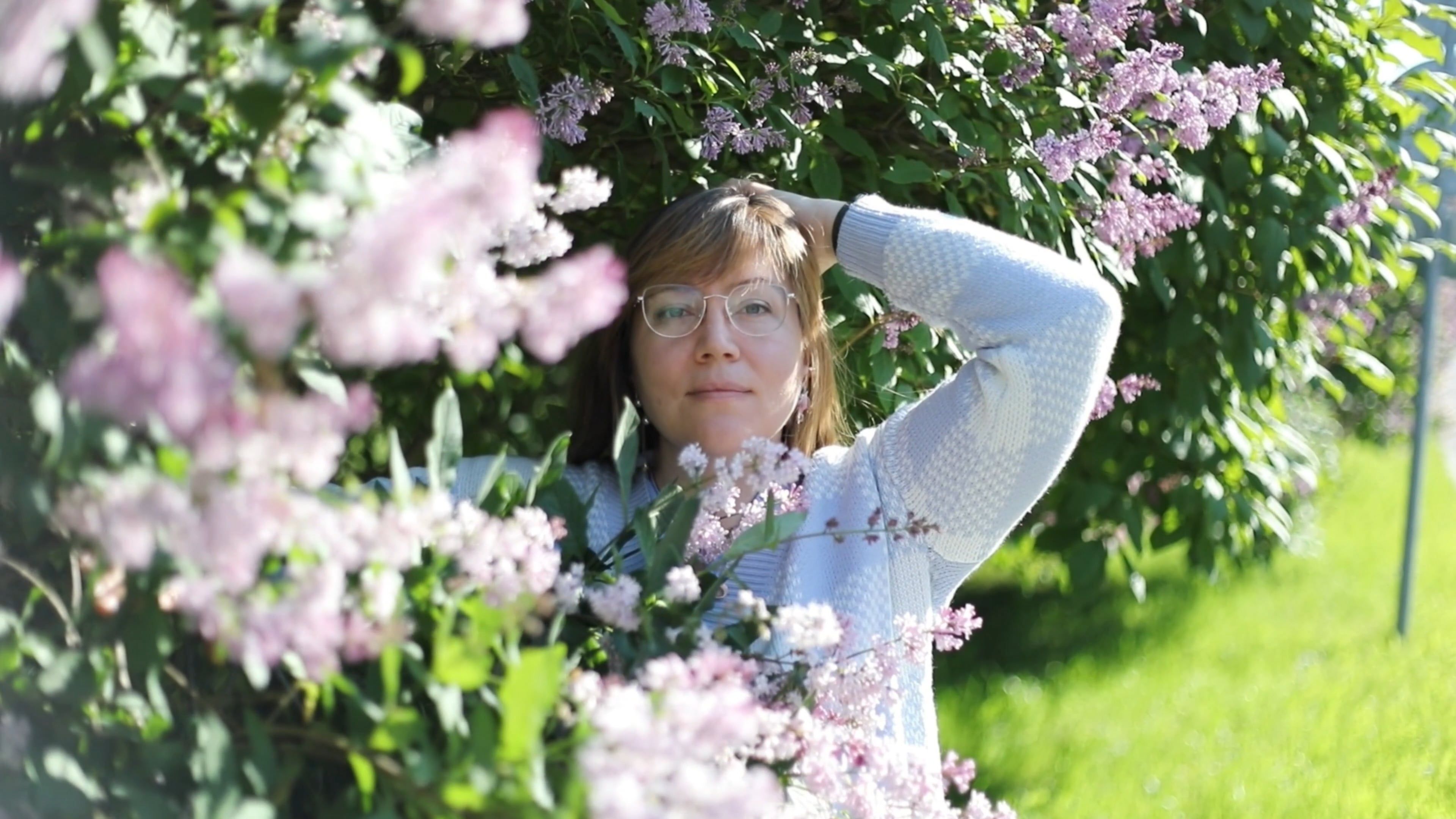 A woman is leaning against a bush with lilas Free Stock Video Footage ...