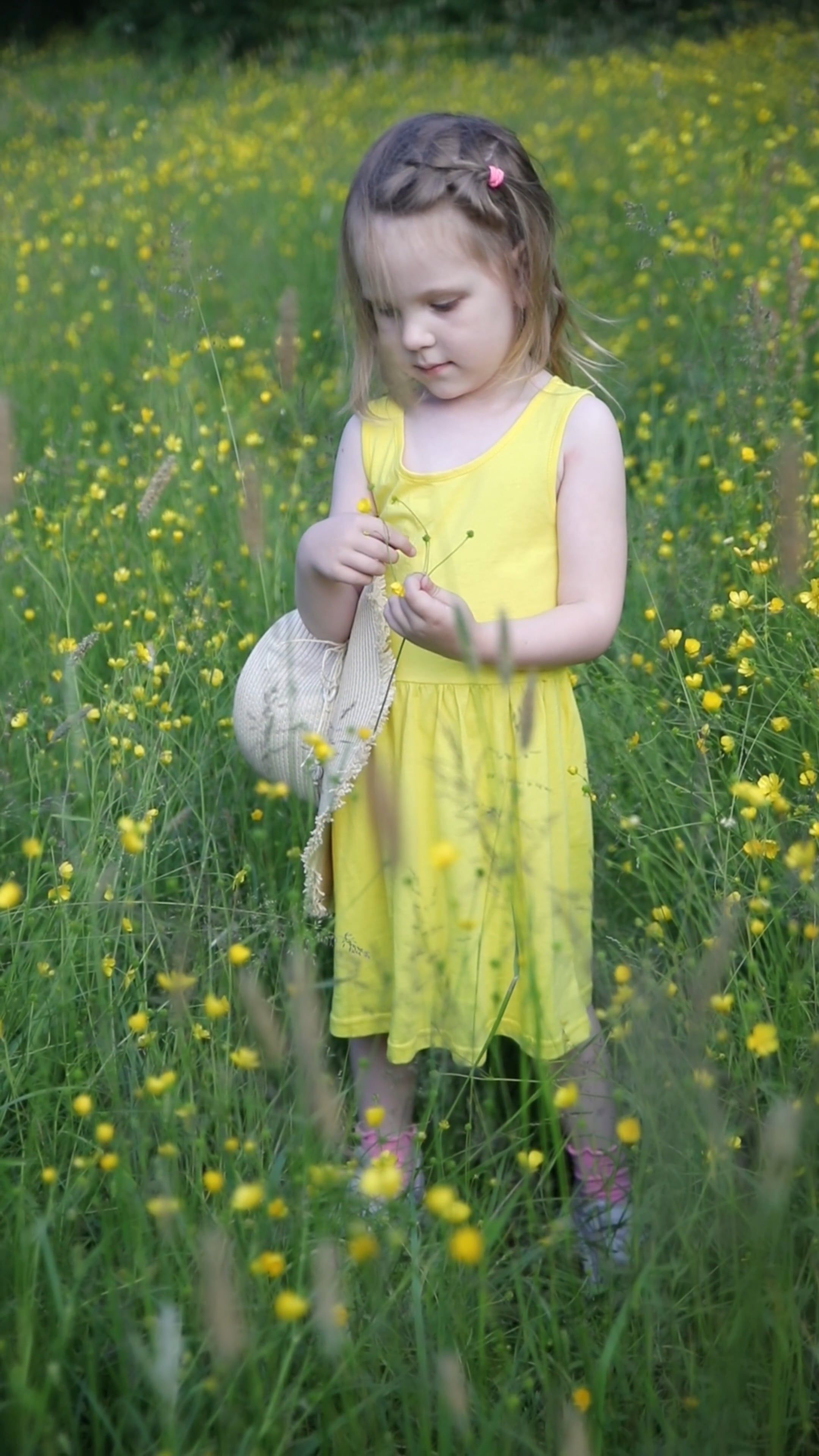 A little girl in a yellow dress is standing in a field of flowers Free ...