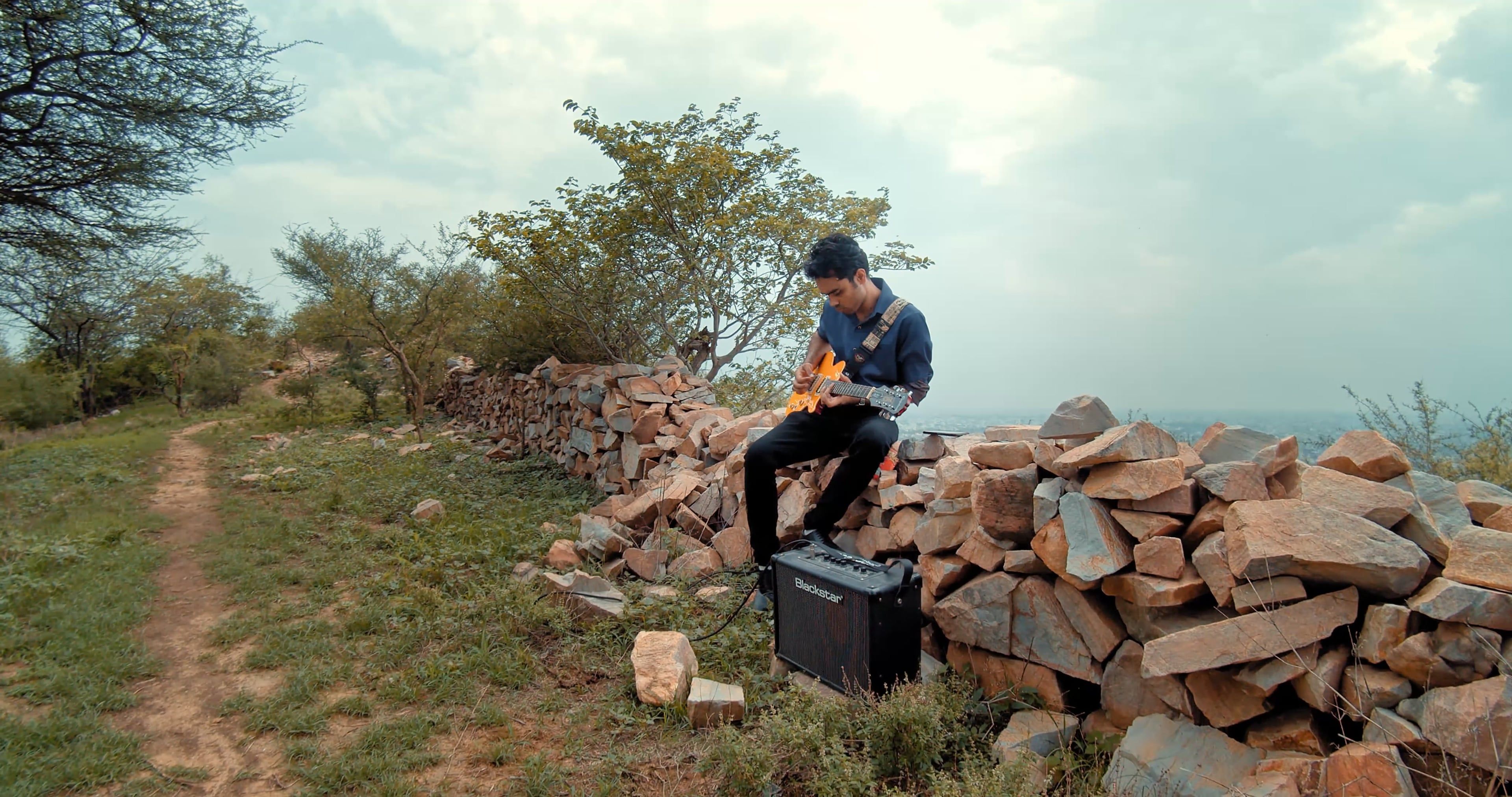 A man sitting on a rock playing an electric guitar Free Stock Video ...