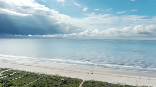 Aerial view of coastline beach and ocean with dark storm cloud on horizon