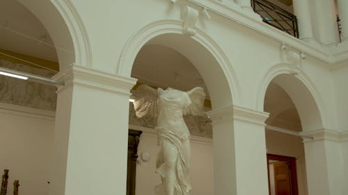 Still shot of statue in hall, under arch 