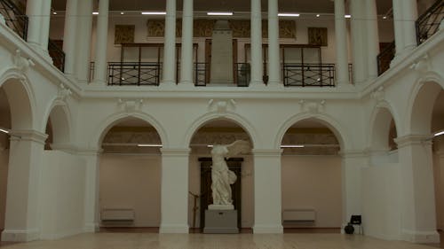 Marble statue in hall with arches and columns 