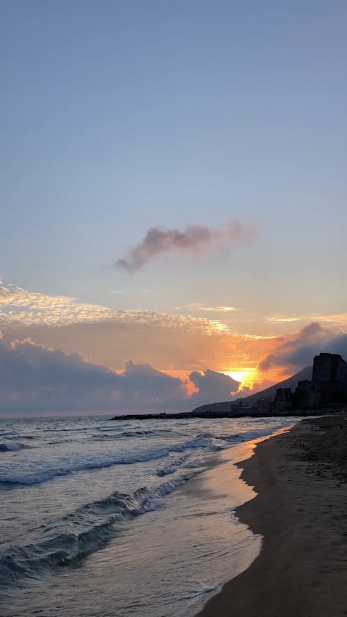 Breaking Waves on a Sandy Beach at Sunset 