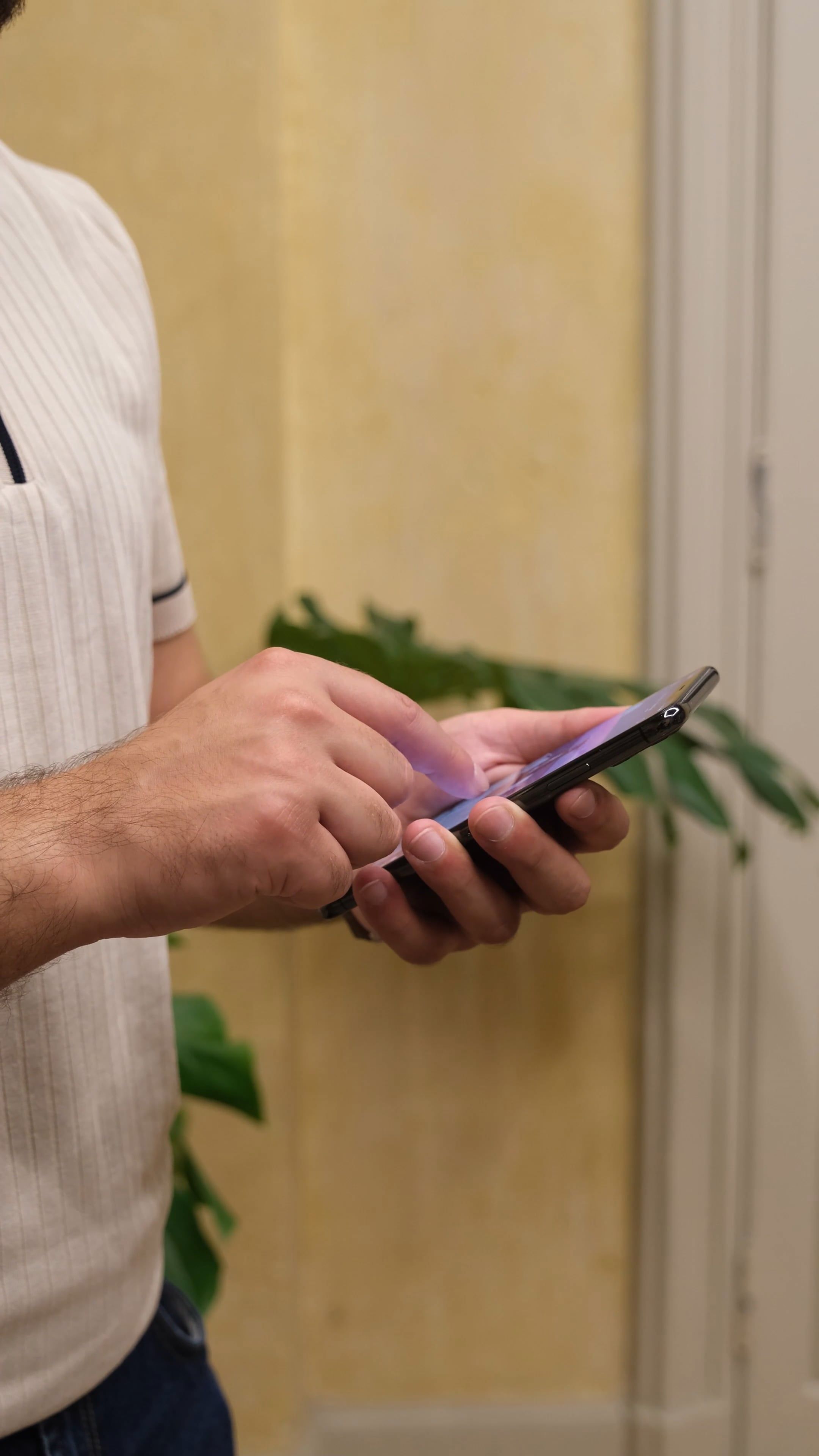 A man in a white shirt and black pants is holding a cell phone Free ...
