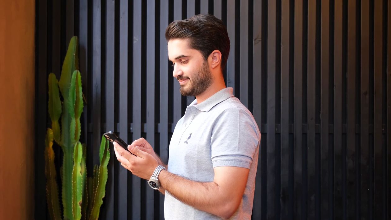 A man standing in front of a potted plant using his cell phone Free ...