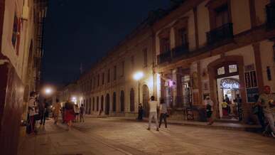 a street at night with people walking and cars driving