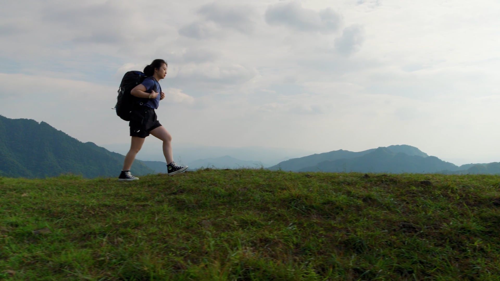 a woman with a backpack is hiking on a mountain 18206418