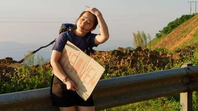a woman holding a sign on a road