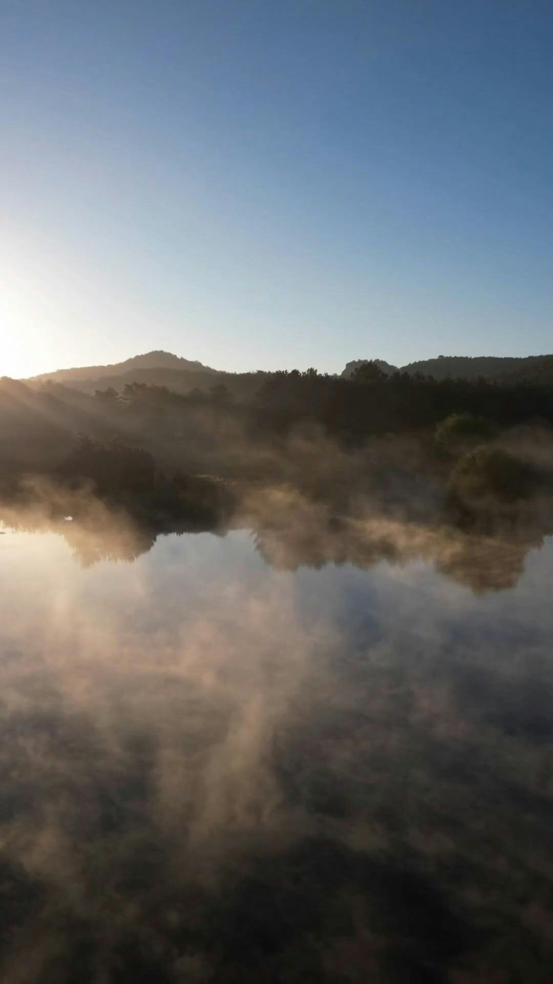 A lake with mist rising from it and the sun setting Free Stock Video ...