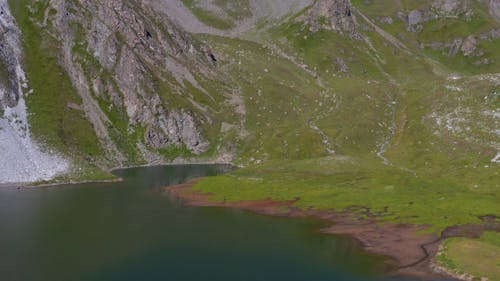 Tignes - Flying with a drone over a beautiful green lake lost in mountains in summer