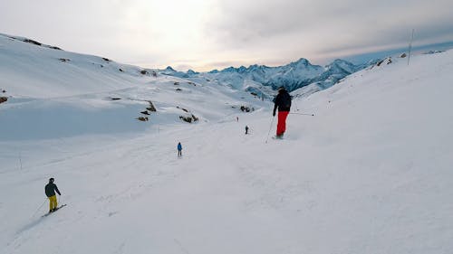 People skiing on a slope with beautiful snowy mountains in background