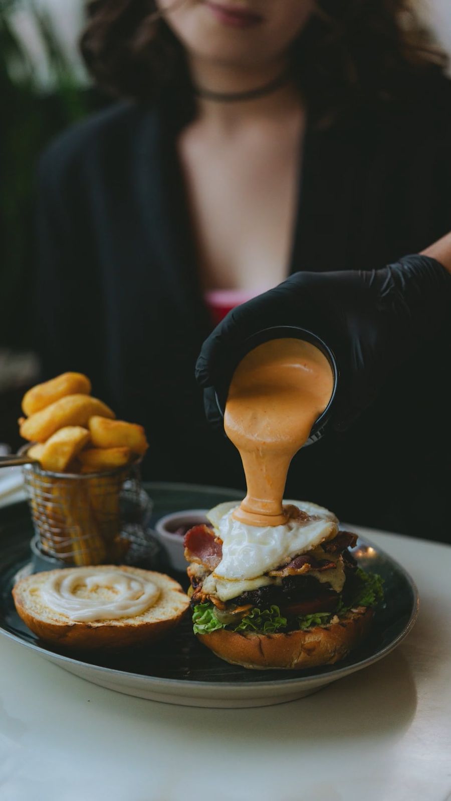 Käsesauce wird über einen Burger gegossen