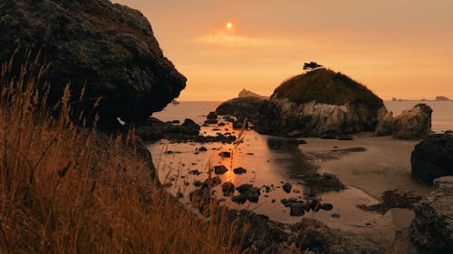 Sunset On Ocean Coast With Rocks And Beach