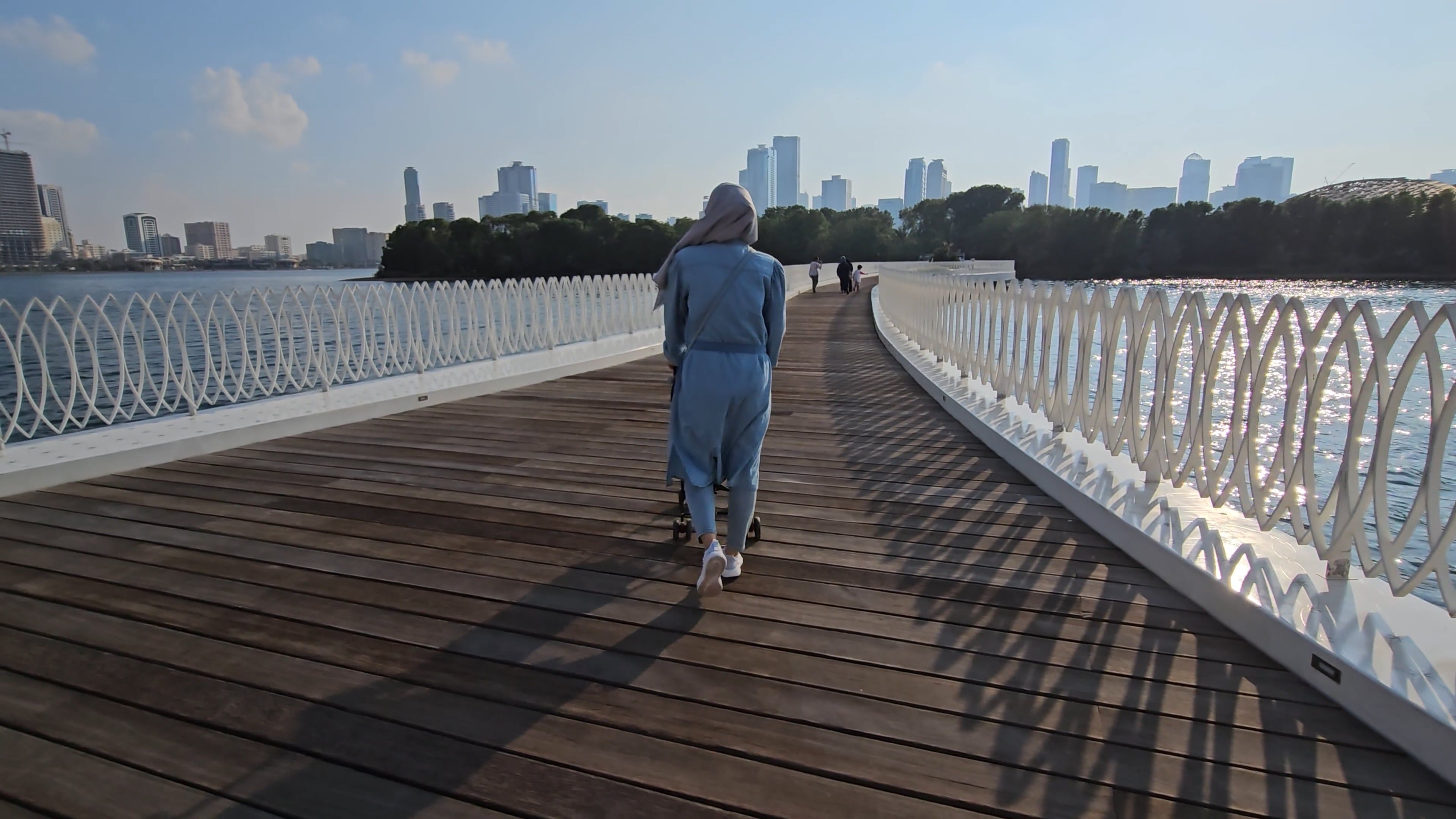 A woman walking on a bridge with a city in the background Free Stock ...