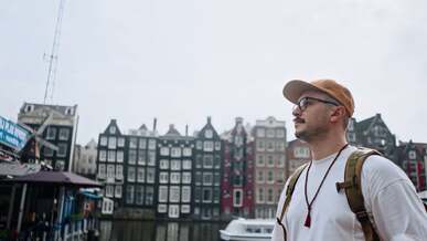 a man with a backpack walks through a city