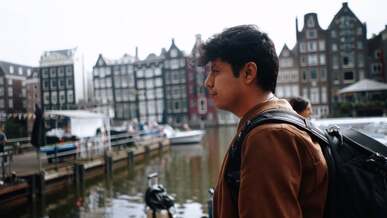 a man with a backpack standing near a canal