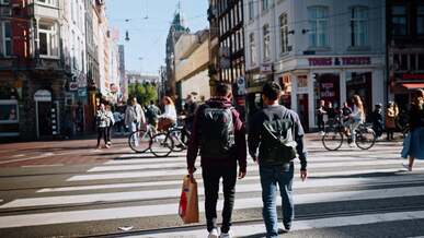 two people walking across a street in a city