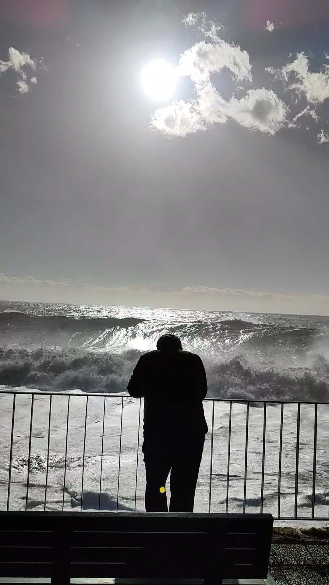 A man is standing on a bench looking out at the ocean Free Stock Video ...