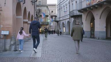 people walking down a cobblestone street in an old town
