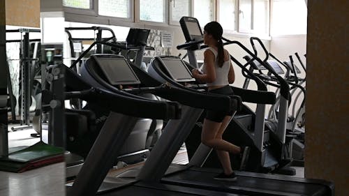 Fit girl runs on a treadmill in the gym