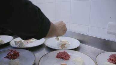 a chef is preparing food on plates in the kitchen