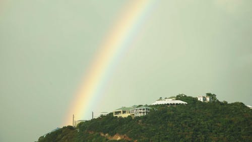 Vibrant rainbow over house on side of cliff