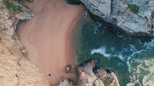 Rotating drone shot of view of Hidden Beach between rocks, Cabo da Roca, Portugal