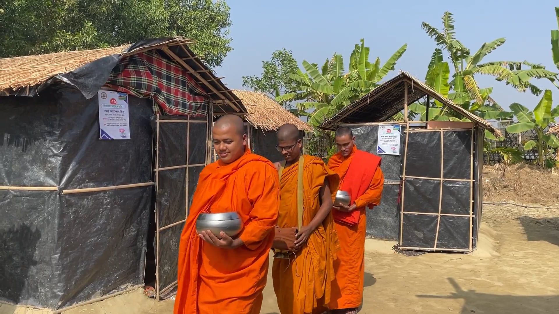 A monk in a orange robe standing in front of a hut Free Stock Video ...