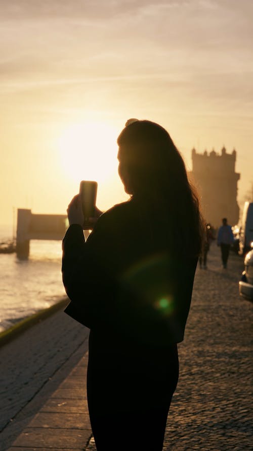 A young girl is taking photos of the Tejo River in Belém, Lisbon