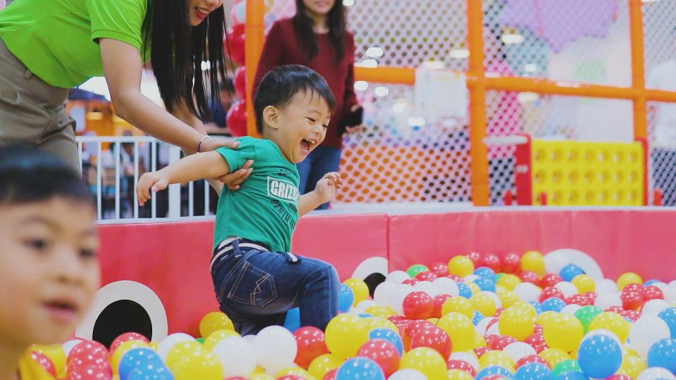 A boy and a girl playing in a colourful ball pit