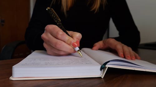 Woman’s hand with beautiful polished fingernails writing down thoughts and ideas on notebook with a pen. Slow motion video of creative woman taking notes. Concept of lifestyle, planning or...