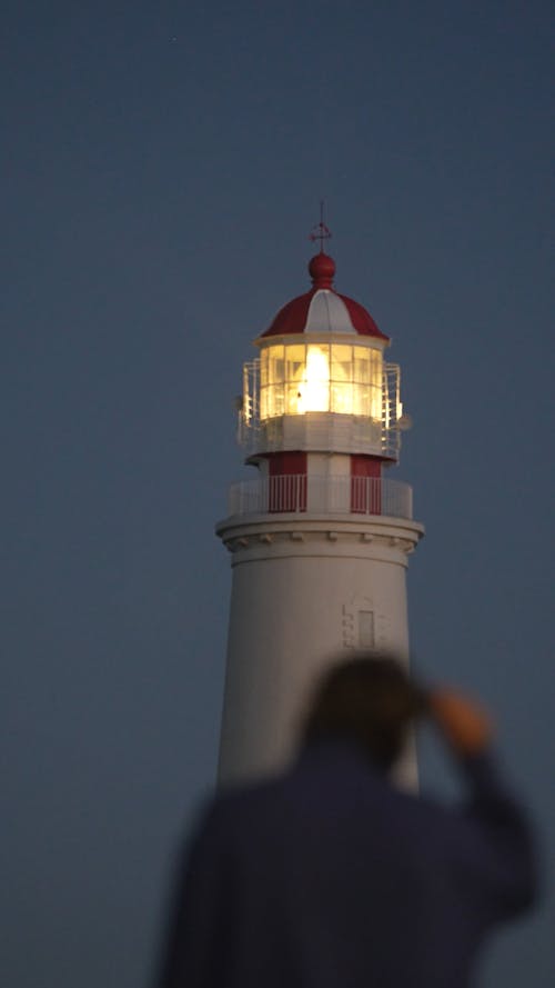 Walking person with a  lighthouse in the background