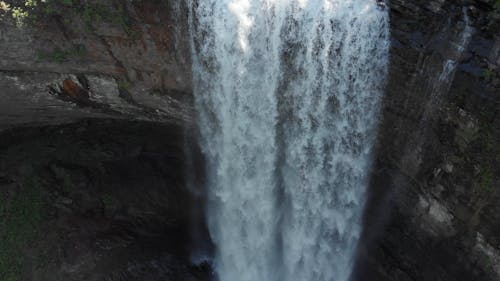 Water Pouring Down A Falls In A Cliff Surrounded By Thick Vegetation