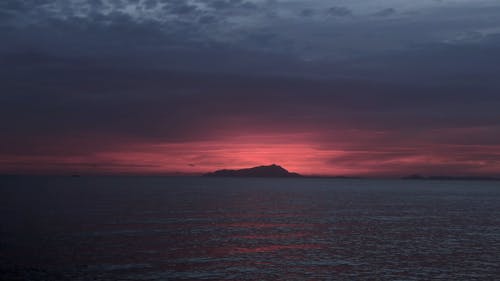 日没時の山のシルエットのビューと水域