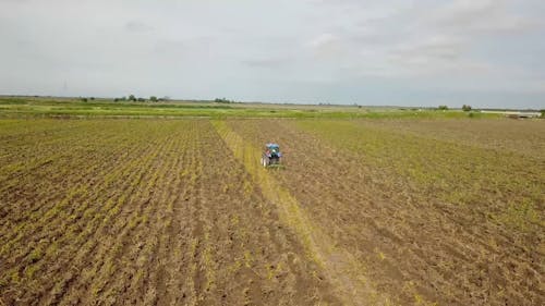 A Person Plowing Cropland Using A Tractor