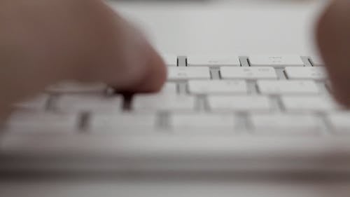 Person Typing Using A White Keyboard