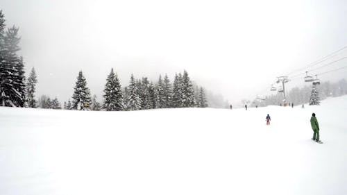 People Skiing The Mountain Slopes On A Snowy Winter's Day